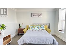 A bedroom with a bed, a yellow chair, and a plant.