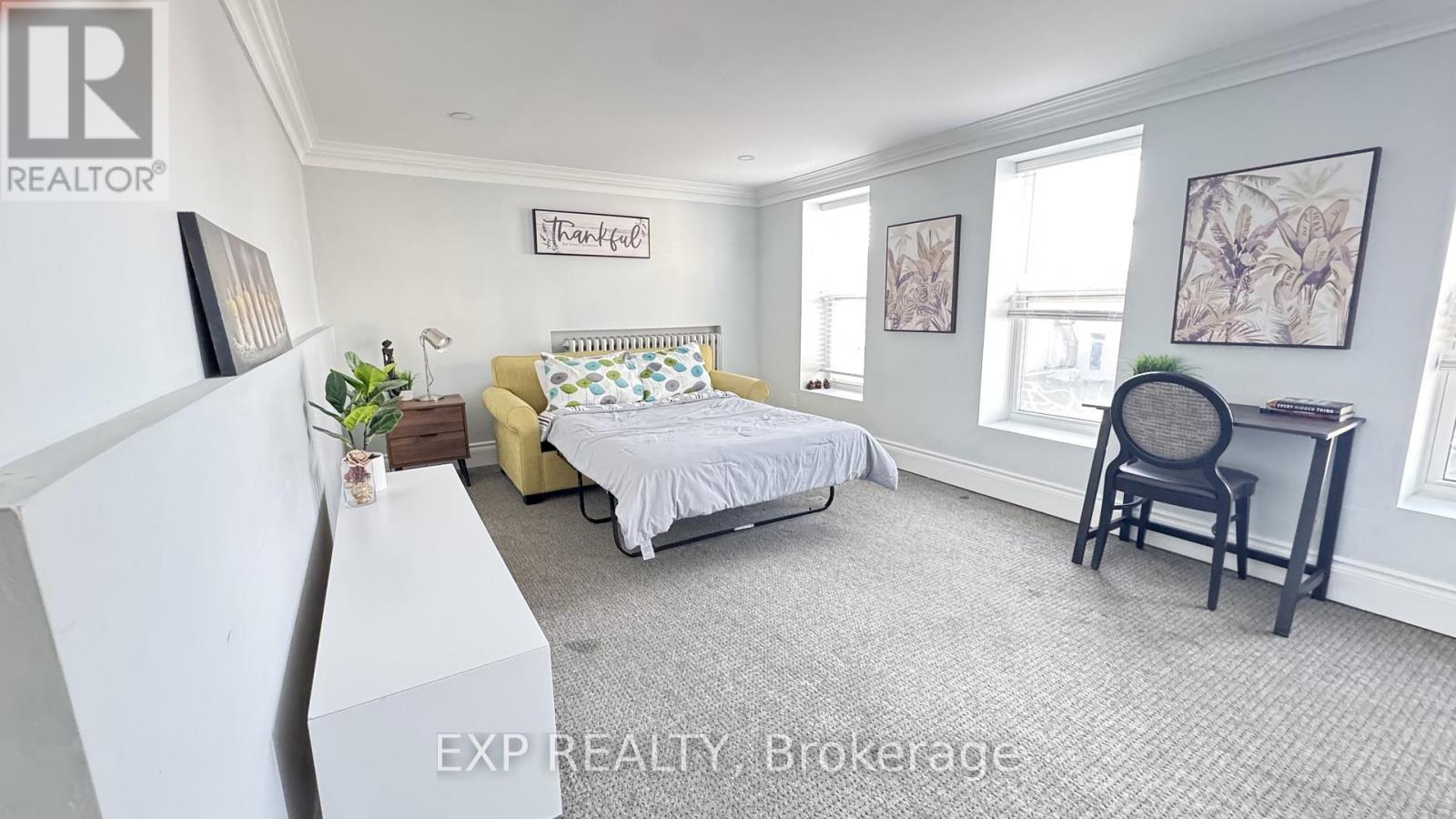 A bedroom with a bed, chair, and a framed picture on the wall.