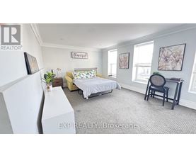 A bedroom with a bed, chair, and a framed picture on the wall.