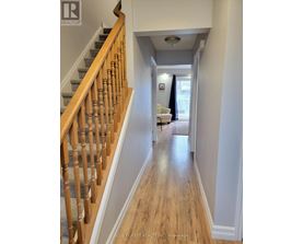 A hallway with a staircase on the left and a living room on the right.