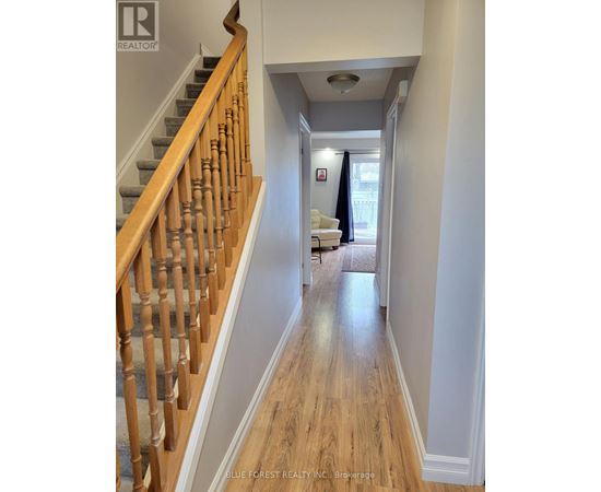A hallway with a staircase on the left and a living room on the right.