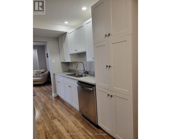 A kitchen with white cabinets and a wooden floor.