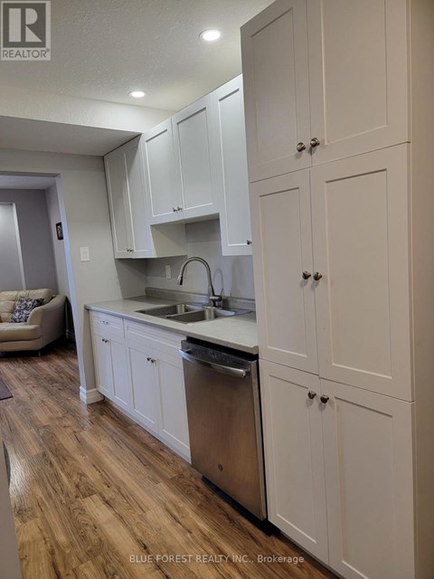 A kitchen with white cabinets and a wooden floor.