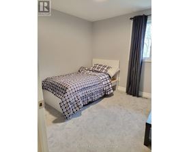 A bedroom with a bed covered in a black and white patterned bedspread.