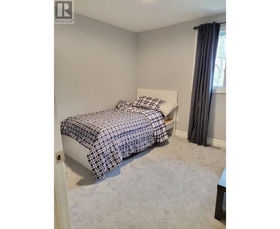 A bedroom with a bed covered in a black and white patterned bedspread.