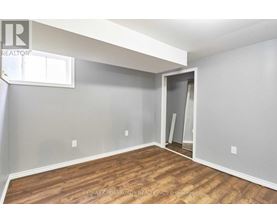 A room with a wooden floor and a grey wall with a window.