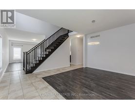 A spacious room with a staircase and a rug on the floor.