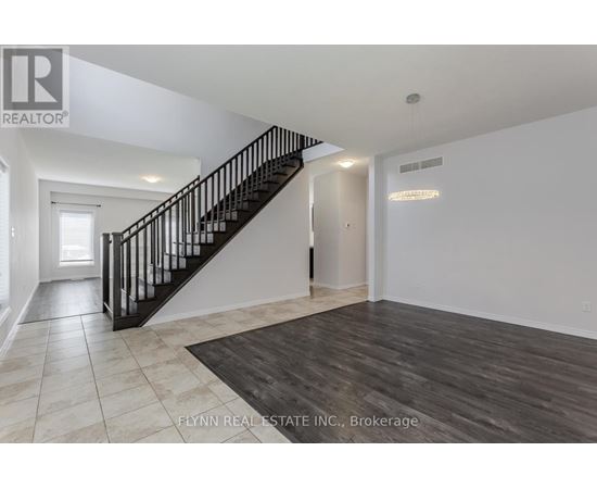 A spacious room with a staircase and a rug on the floor.
