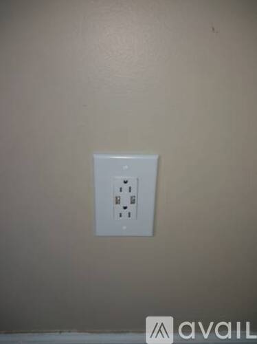 A white electrical outlet on a beige wall.