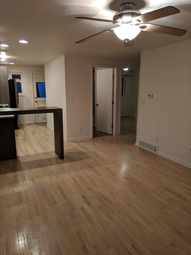 A room with a ceiling fan and wooden floors.
