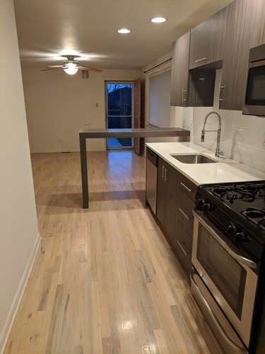 A kitchen with a black stove top oven and wooden flooring.