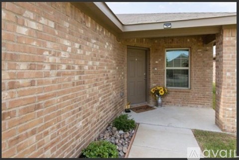 A brick house with a grey door and a small garden in front.