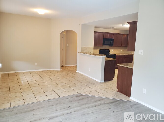 A spacious living room with a kitchen area in the background.