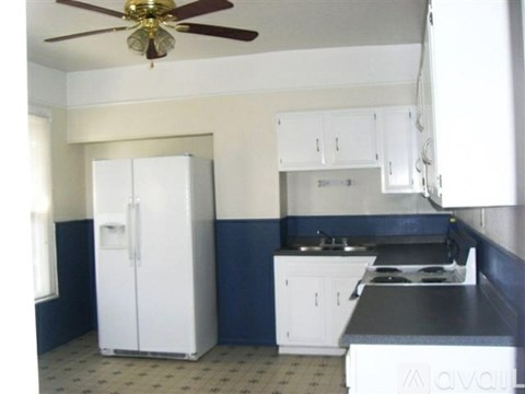A kitchen with a white fridge and a black counter top.
