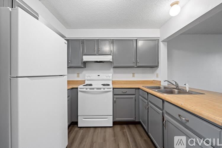A kitchen with a white fridge, white oven, and grey cabinets.