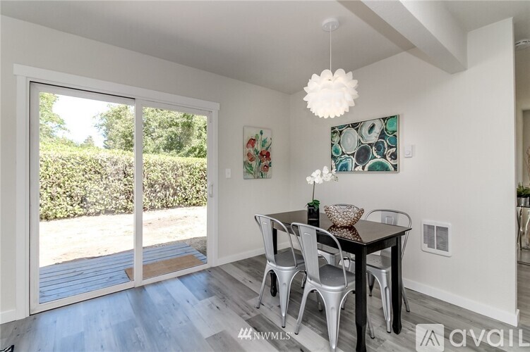 A dining room with a table and chairs and a painting on the wall.