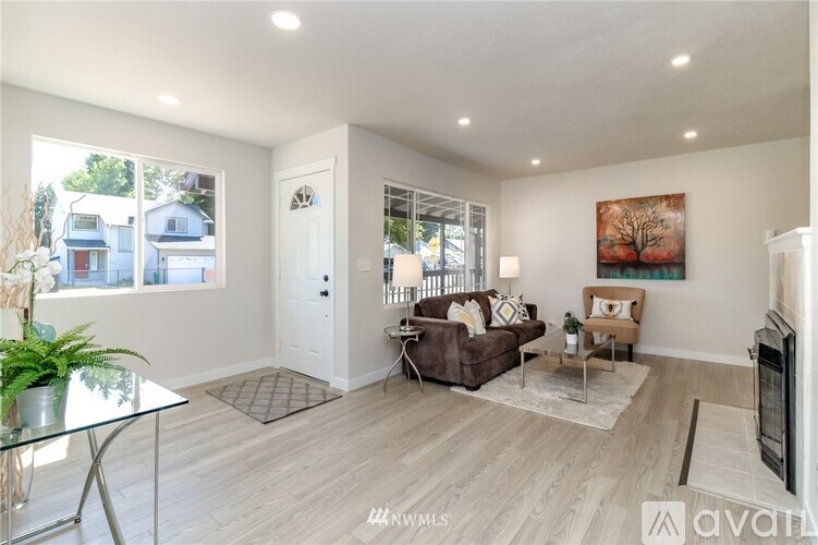 A spacious living room with a glass table and a brown couch.
