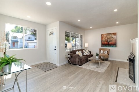 A spacious living room with a glass table and a brown couch.