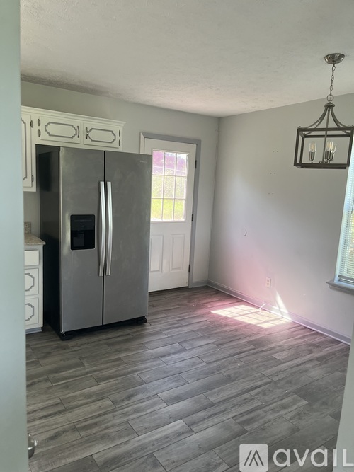 A kitchen with a fridge and a hanging light fixture.