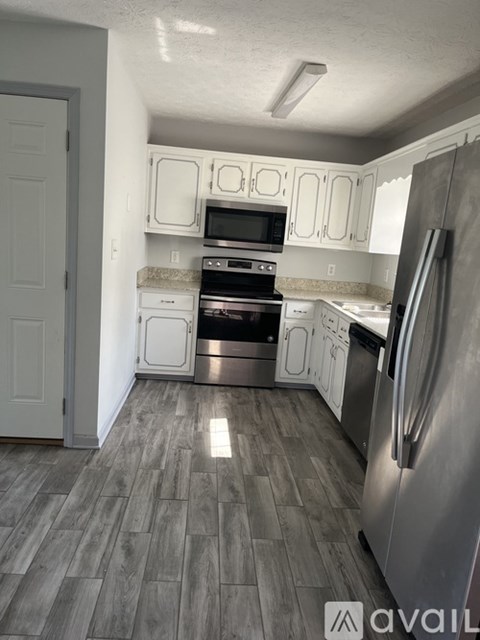 A kitchen with a refrigerator, oven, and microwave.