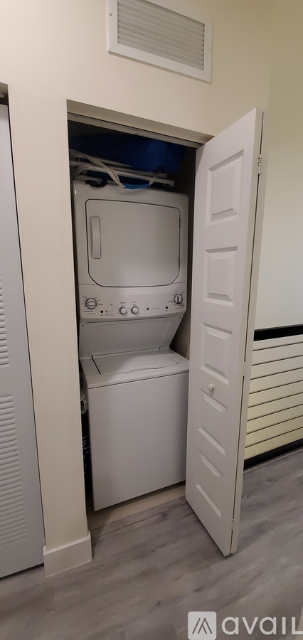 A white washing machine is tucked into a small space under a door.