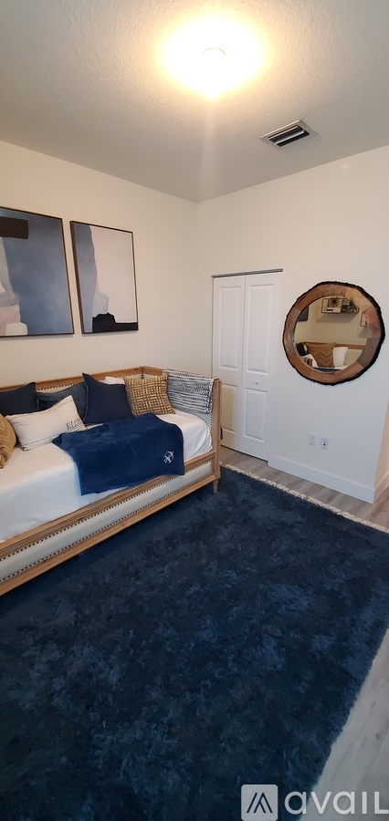 A bedroom with a bed, blue carpet, and a mirror on the wall.