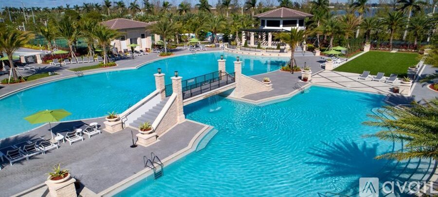 A large outdoor swimming pool surrounded by palm trees and lounge chairs.