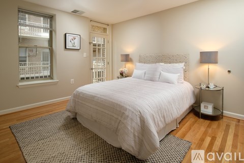 A bedroom with a large bed and a window with blinds.