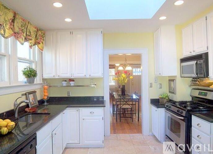 A kitchen with white cabinets and black countertops.