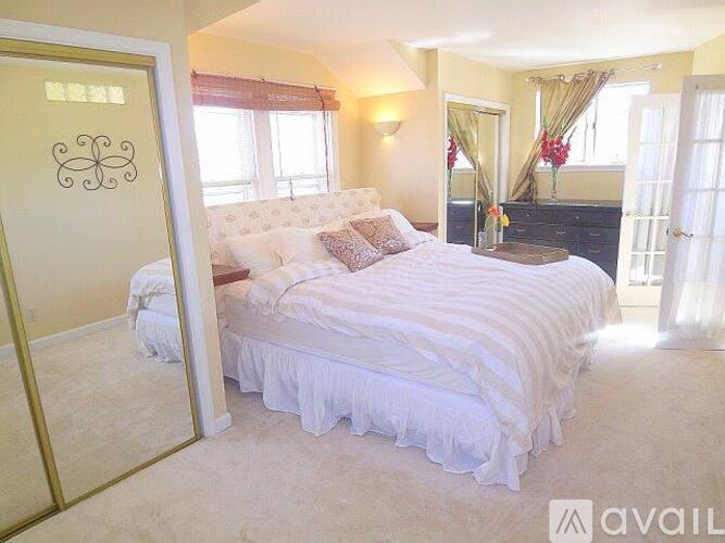 A bedroom with a large bed and a mirror on the wall.