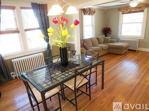 A living room with a glass table and chairs, a vase of flowers, and a couch.