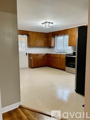 A kitchen with wooden cabinets and a black refrigerator.
