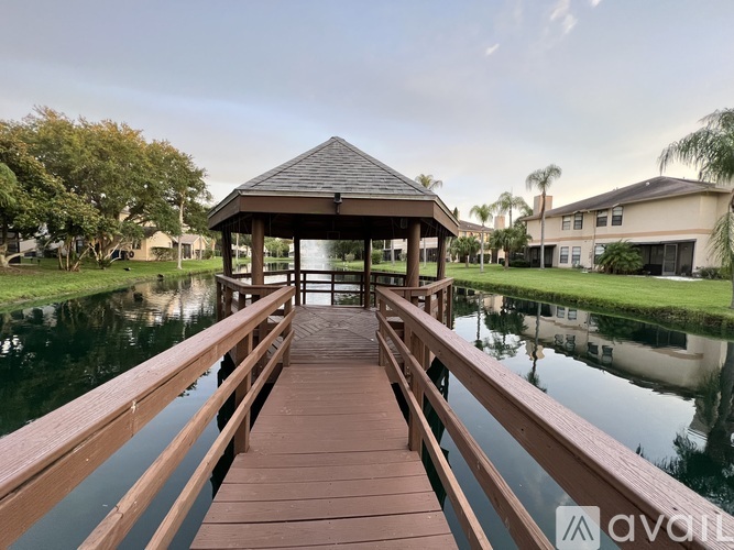 A wooden dock leads to a gazebo over a calm body of water.