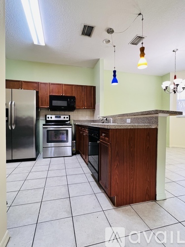 A kitchen with a refrigerator, microwave, oven, and sink.
