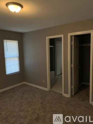 A room with a carpeted floor and a window with blinds.