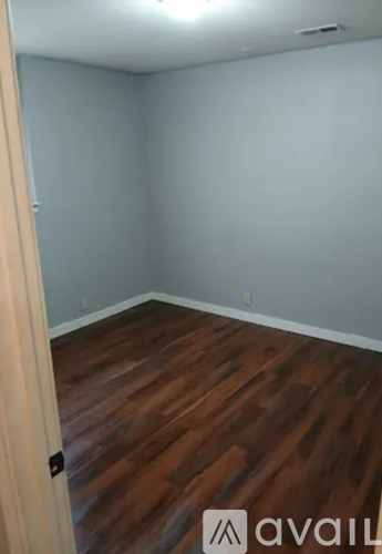 A room with wooden flooring and a door on the left.