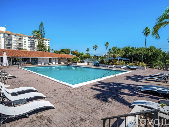 A pool surrounded by sun loungers and palm trees.