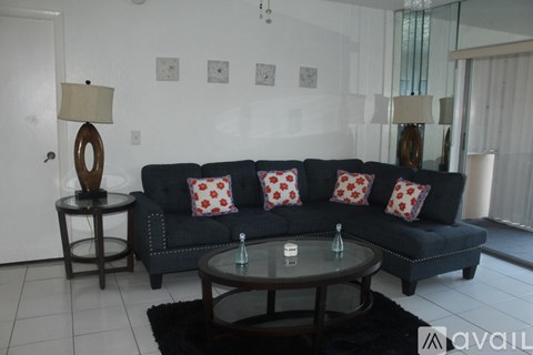 A living room with a black couch and a round table.