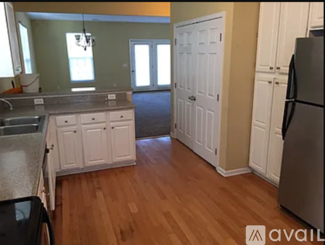 A kitchen with white cabinets and a wooden floor.