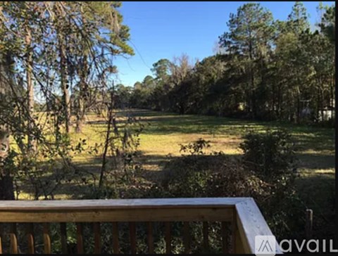 A view from a balcony overlooking a grassy field and trees.