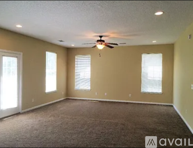 A spacious room with a ceiling fan and carpeted floor.