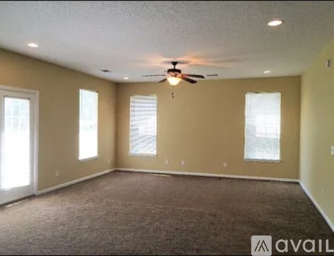 A spacious room with a ceiling fan and carpeted floor.