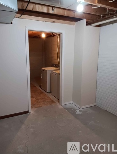 A room with a doorway leading to another room with a table and a cabinet.