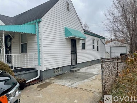 A white house with a green awning is for sale.