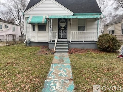 A small white house with a green awning and a porch.