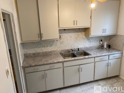 A kitchen with white cabinets and a marble countertop.