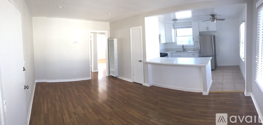 A large open living space with wood flooring and white walls.
