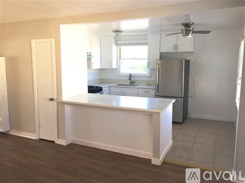 A kitchen with white cabinets and a stainless steel refrigerator.