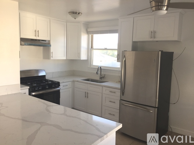 A kitchen with white cabinets and a marble countertop.