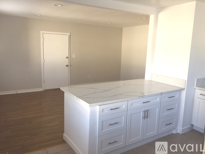 A kitchen with white cabinets and a marble countertop.
